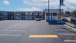 A parking lot with a building labeled "Inn & Suites" and a sign for "Inland". -  Inland Inn & Suites (San Bernardino)