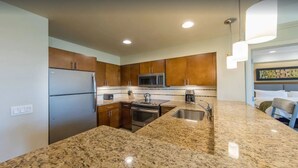 Una cocina moderna con encimeras de granito, electrodomésticos de acero inoxidable y armarios de madera.