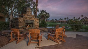 Un área de estar al aire libre con sillas Adirondack y una chimenea de piedra.