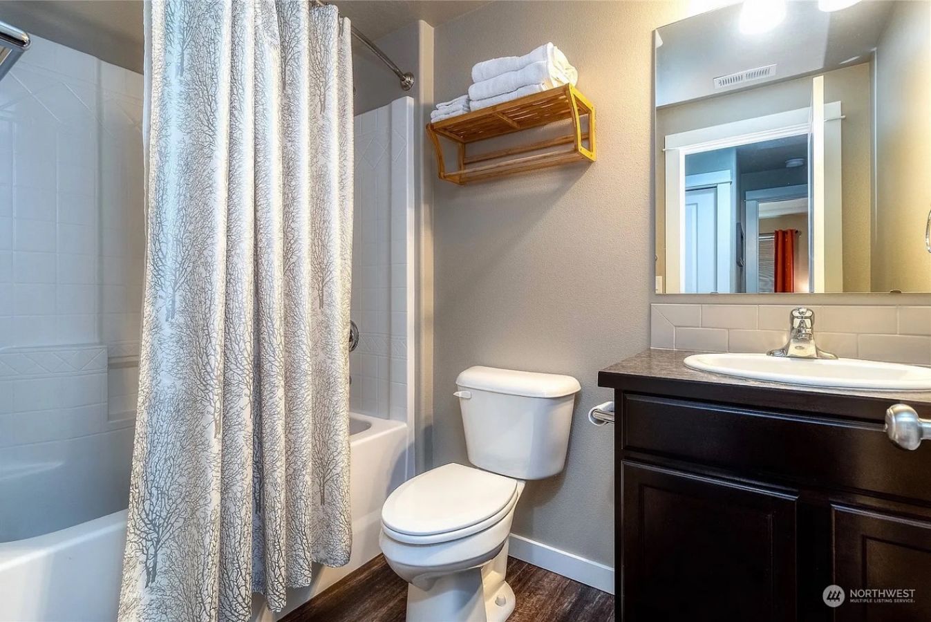 A bathroom with a shower curtain, toilet, and vanity with a mirror.