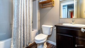 A bathroom with a shower curtain, toilet, and vanity with a mirror.