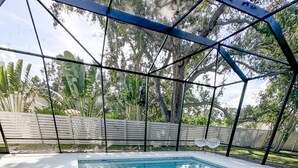 A swimming pool with a geometric metal roof structure, surrounded by a fence and trees. - City Escape near Sarasota Downtown (Sarasota)