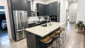 A modern kitchen with a central island, stainless steel appliances, and dark cabinetry. - City Escape near Sarasota Downtown (Sarasota)