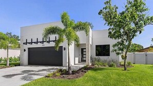 A modern two-story house with a garage, a well-maintained lawn, and a few palm trees. - City Escape near Sarasota Downtown (Sarasota)