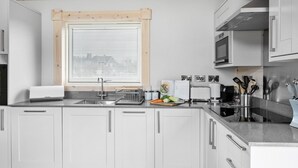 Een moderne keuken met witte kasten, een roestvrijstalen spoelbak, een magnetron en een broodrooster.