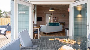 Een gezellig interieur met een eethoek, een bank en een keuken, zichtbaar door een geopende deur.