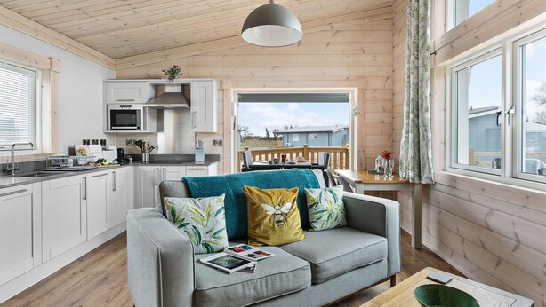 Een moderne keuken met witte kasten en een eethoek met een houten tafel en stoelen.