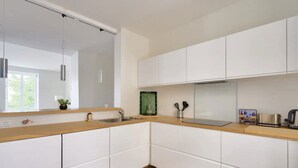 A modern kitchen with white cabinets, a wooden countertop, a sink, and a stove. - Charming town house completely renovated (Quimper)