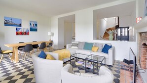 A modern living room with a checkered floor, a white sofa with colorful cushions, a wooden dining table with chairs, and a coffee table. - Charming town house completely renovated (Quimper)