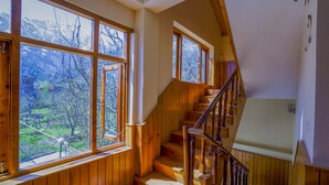 A wooden staircase with large windows offering a view of a mountainous landscape.