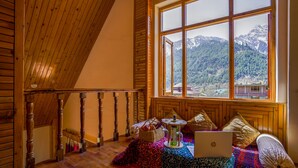 A wooden staircase leading to a room with a large window offering a mountain view.