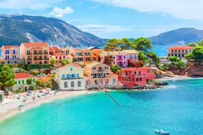 Un pueblo costero con edificios de colores, una playa y un barco en el agua.