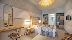 Un dormitorio moderno con cama, mesita de noche, silla y un espejo grande.