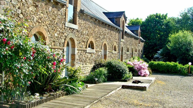 A stone building with arched windows and a wooden deck. - Les Cavaliers, character gîte with swimming pool, 20 minutes from the seaside (La Poterie, Lamballe)