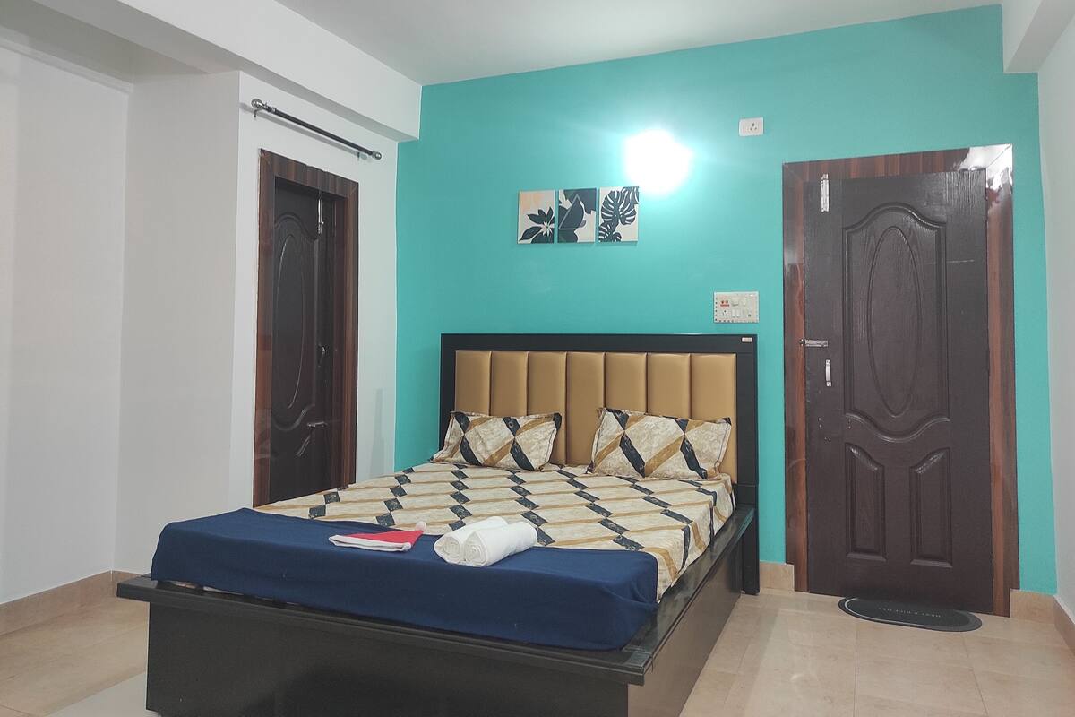 A bedroom with a bed, a door, a ceiling fan, and a wall-mounted light.