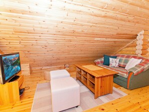 A cozy wooden interior with a sofa, a small table, and a television on a wooden stand. - Kaakkuri by Interhome (Lieksa)