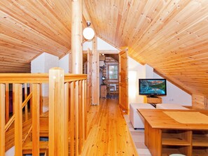 Un intérieur en bois avec une télévision, des meubles en bois et un escalier menant à une autre pièce.