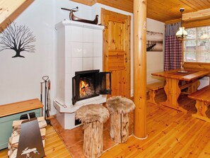 A cozy room with a fireplace, wooden furniture, and a dining table. - Kaakkuri by Interhome (Lieksa)