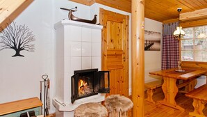 A cozy cabin interior with a fireplace, wooden furniture, and a dining area.