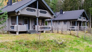 A log cabin with a porch and a smaller attached structure.