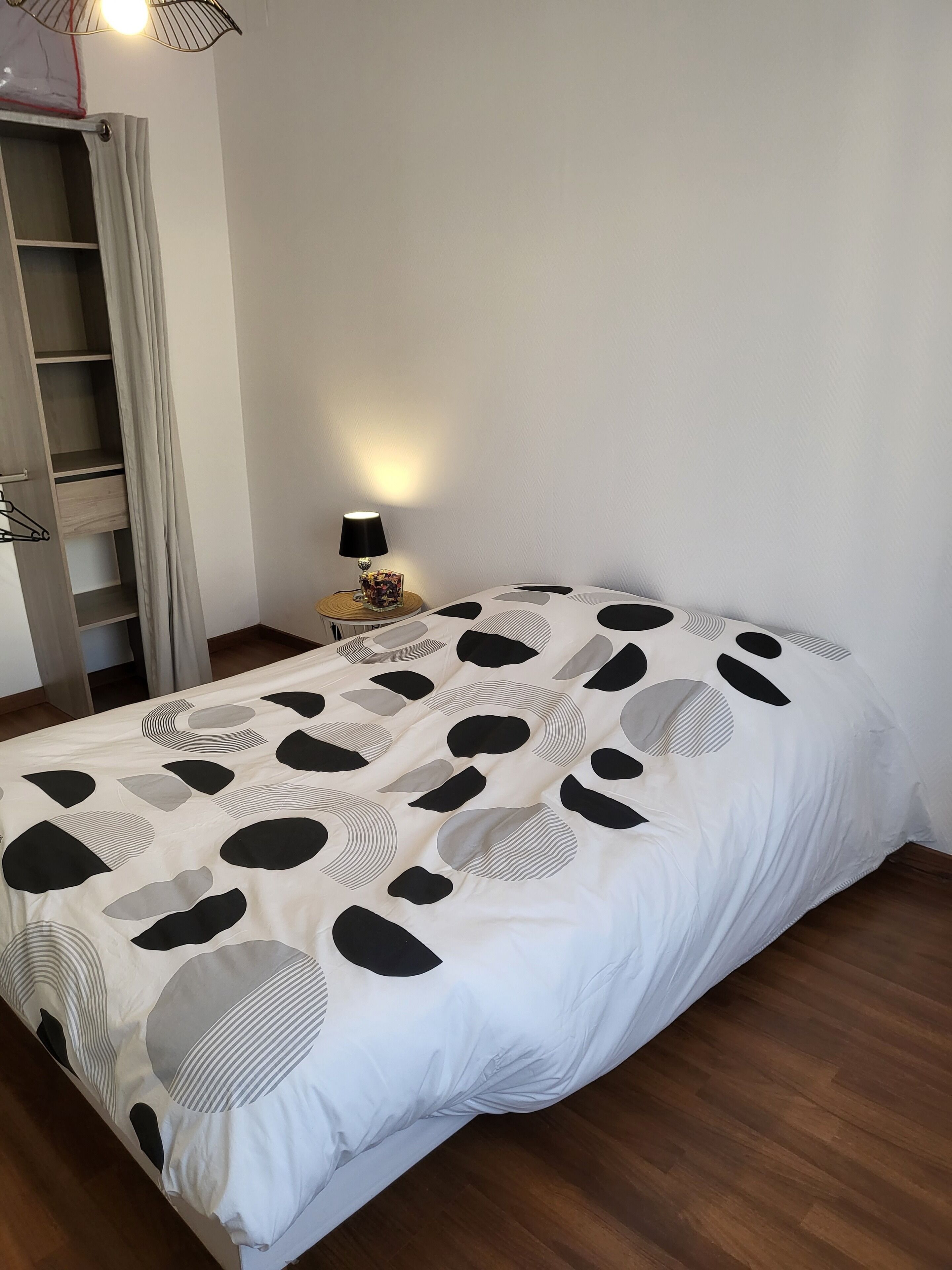 Une chambre à coucher avec un lit, une table de chevet, une lampe et une armoire.