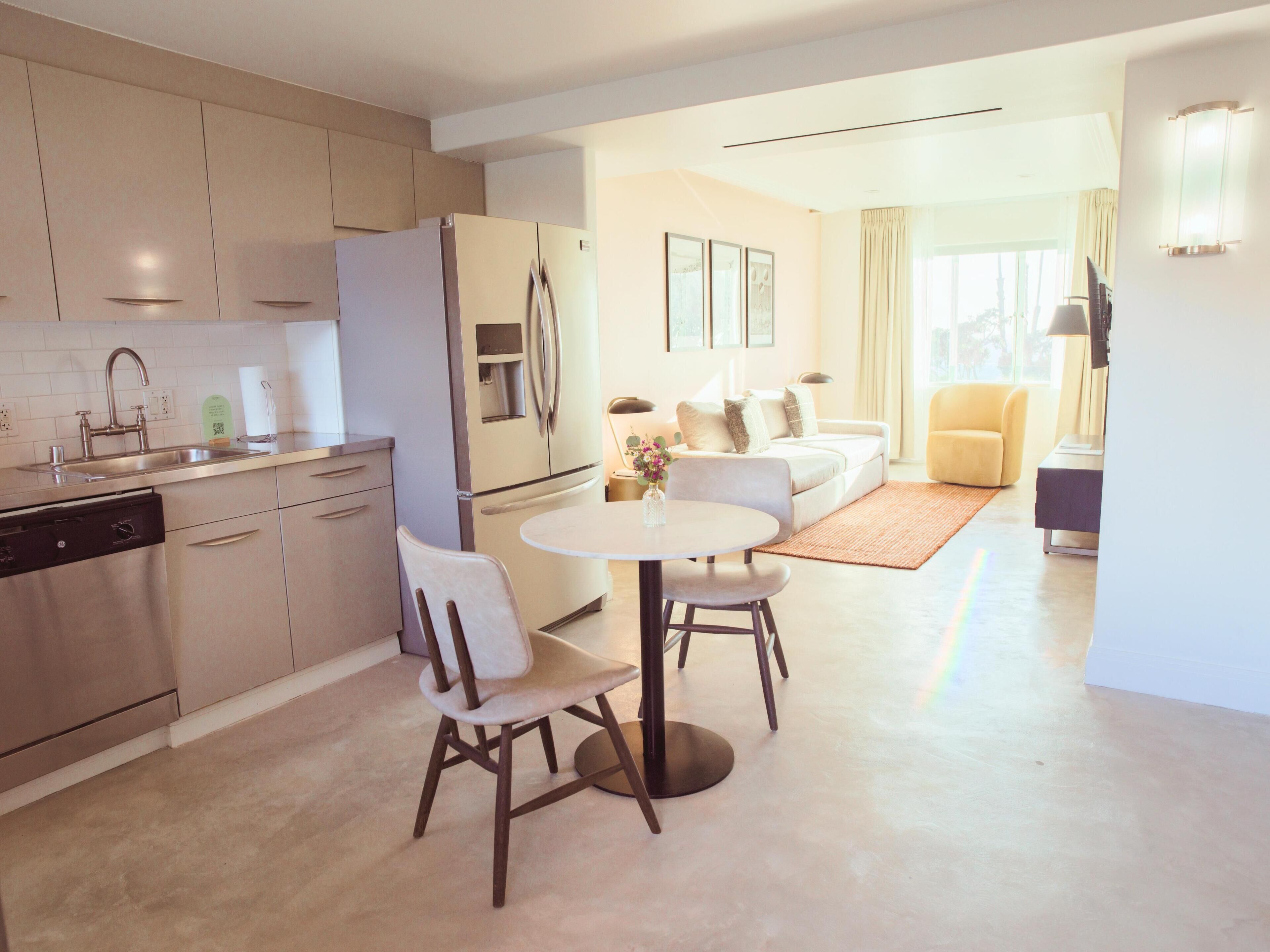 A modern kitchen with a dining area, a sofa, and a chair.