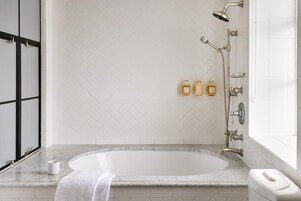 A bathroom with a bathtub, a shower, and two bottles of shampoo on the counter.