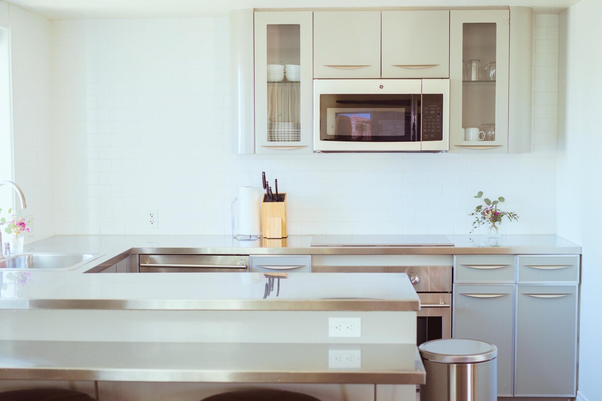 A modern kitchen with a central island, stainless steel appliances, and a microwave above cabinets.