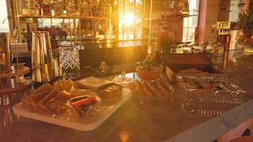 Un espace bar proposant une variété de boissons et d’en-cas, notamment un plateau de hors-d’œuvre et un saladier de fruits.