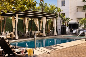 Una piscina al aire libre, camas de piscina con cargo, sombrillas
