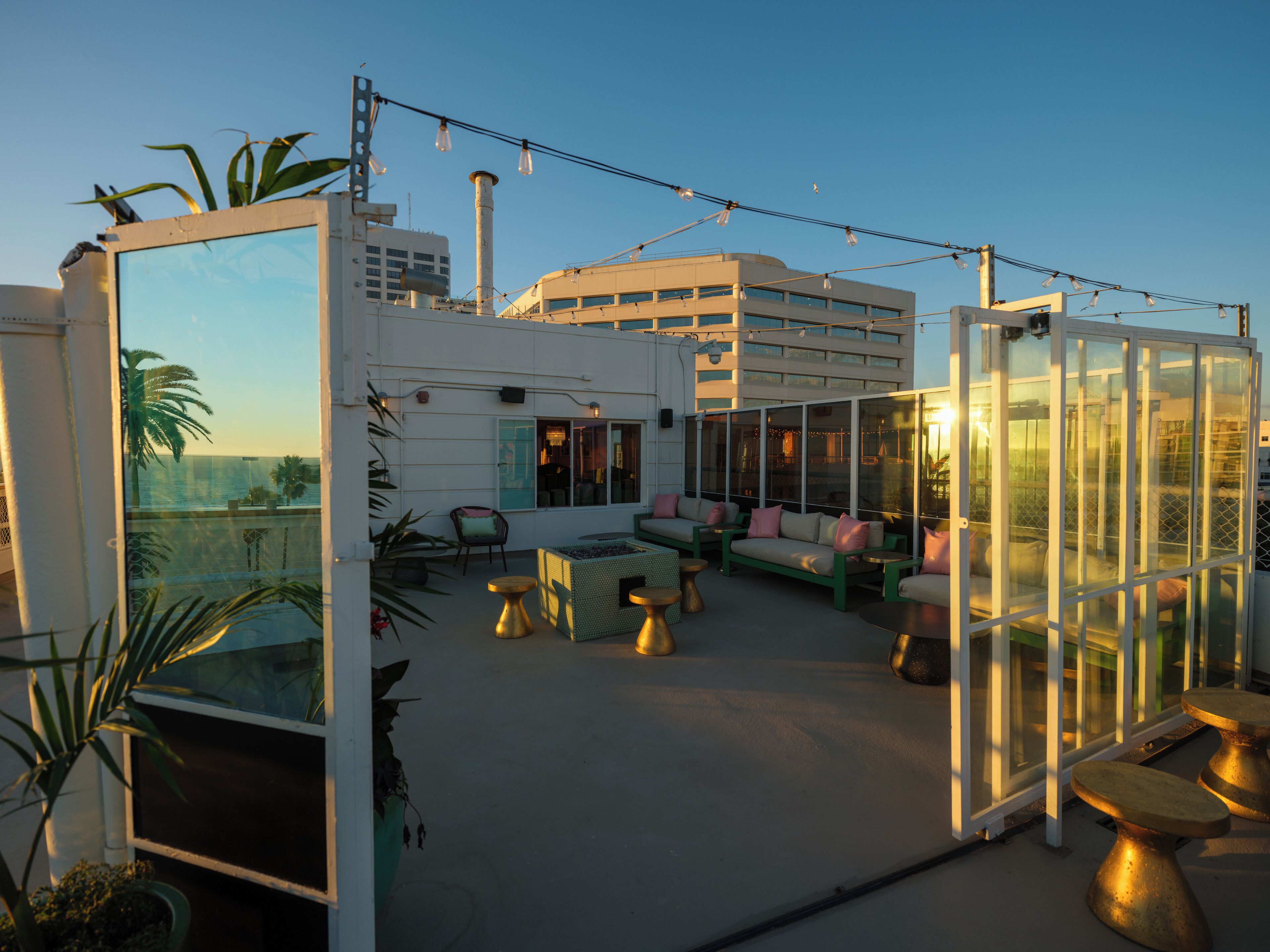 Una terraza en la azotea con zonas de estar, cerramiento de vidrio y vistas al horizonte de la ciudad.