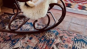 L’intérieur d’un chalet en bois, avec un fauteuil à bascule, un canapé en cuir et un tapis à motifs.