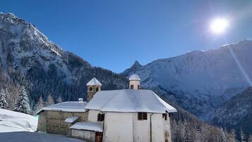 A snow-covered church with a bell tower and a dome, surrounded by snow-covered mountains and trees.