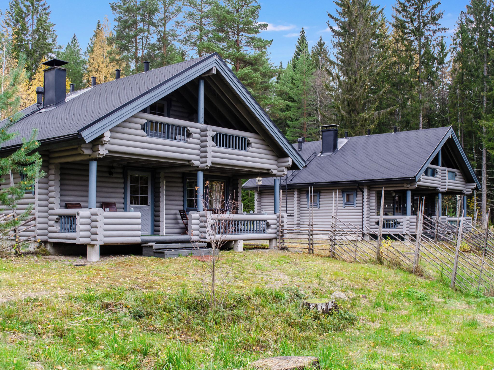 A log cabin with a porch and a separate cabin with a sloped roof.