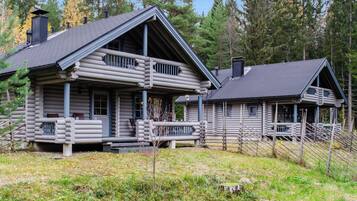 A log cabin with a porch and a separate cabin with a sloped roof.