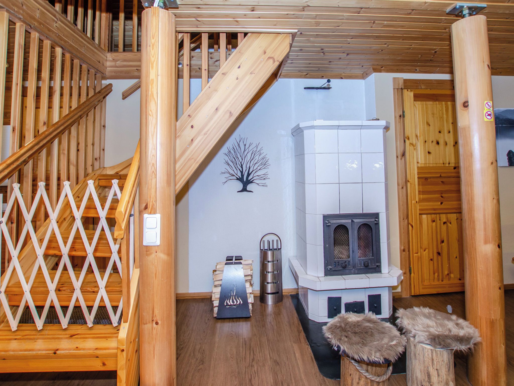 Una escalera de madera conduce a una zona superior con chimenea y una pared decorativa con motivos vegetales.