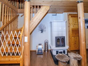 A wooden staircase leading to a lofted area with a fireplace and a decorative tree wall.
