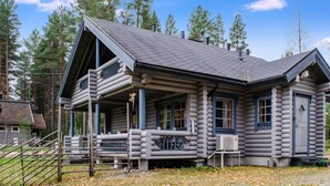A log cabin with a porch, a chimney, and a window.