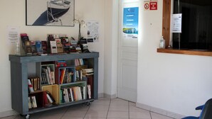 A reception area with a desk, a bookshelf, a framed picture of a boat on a beach, and a no smoking sign.