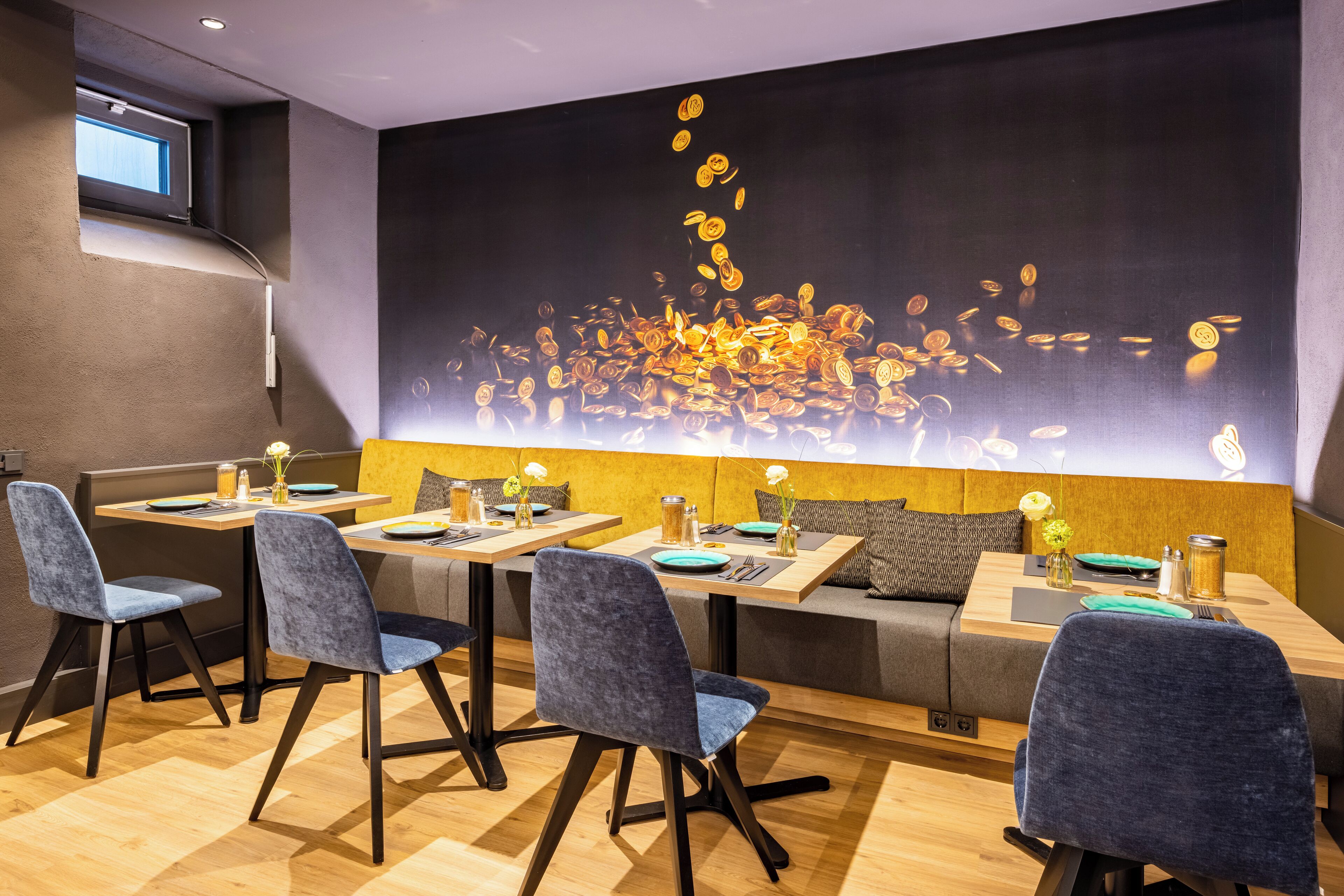 A modern dining area with a large wall mural, wooden tables, and blue upholstered chairs.