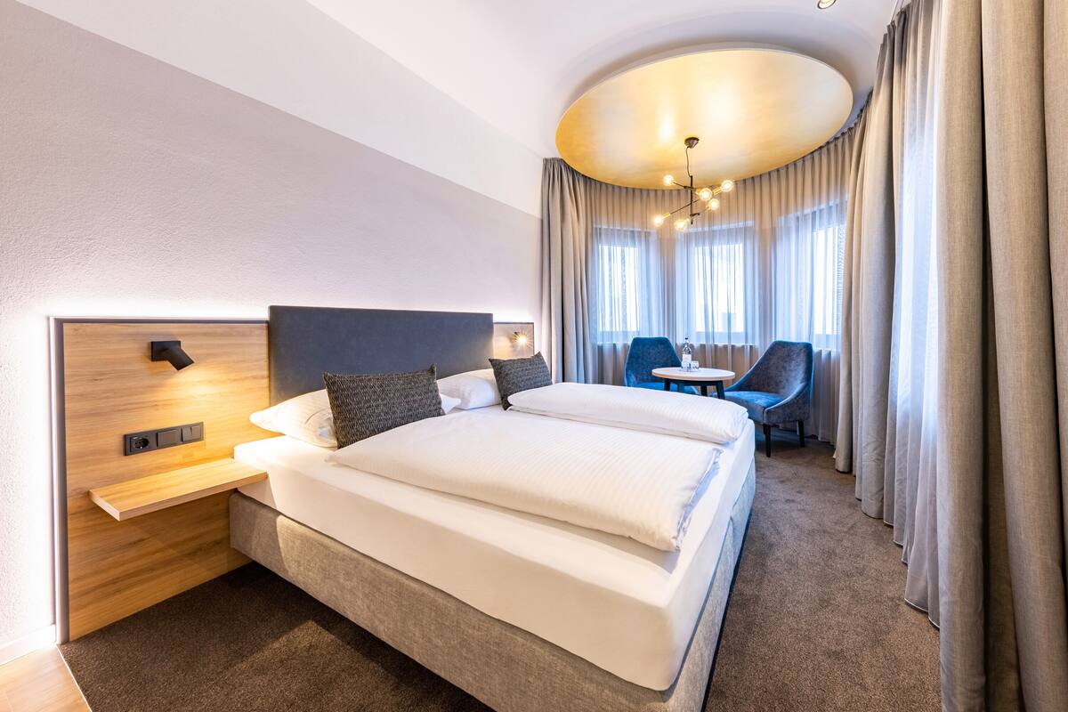 A modern hotel room with a large bed, a desk, and a chair.
