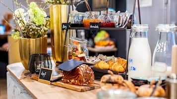 Ein reichhaltiges Frühstücksbuffet mit einer Auswahl an Speisen, darunter Backwaren, Früchten und Getränken.