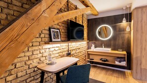 A modern bathroom with a brick wall, wooden beams, a sink, and a mirror with a circular light. - BOLLWERK Lifestyle Hotel - automatisiertes Hotel mit Self Check In (Immenstadt im Allgaeu)