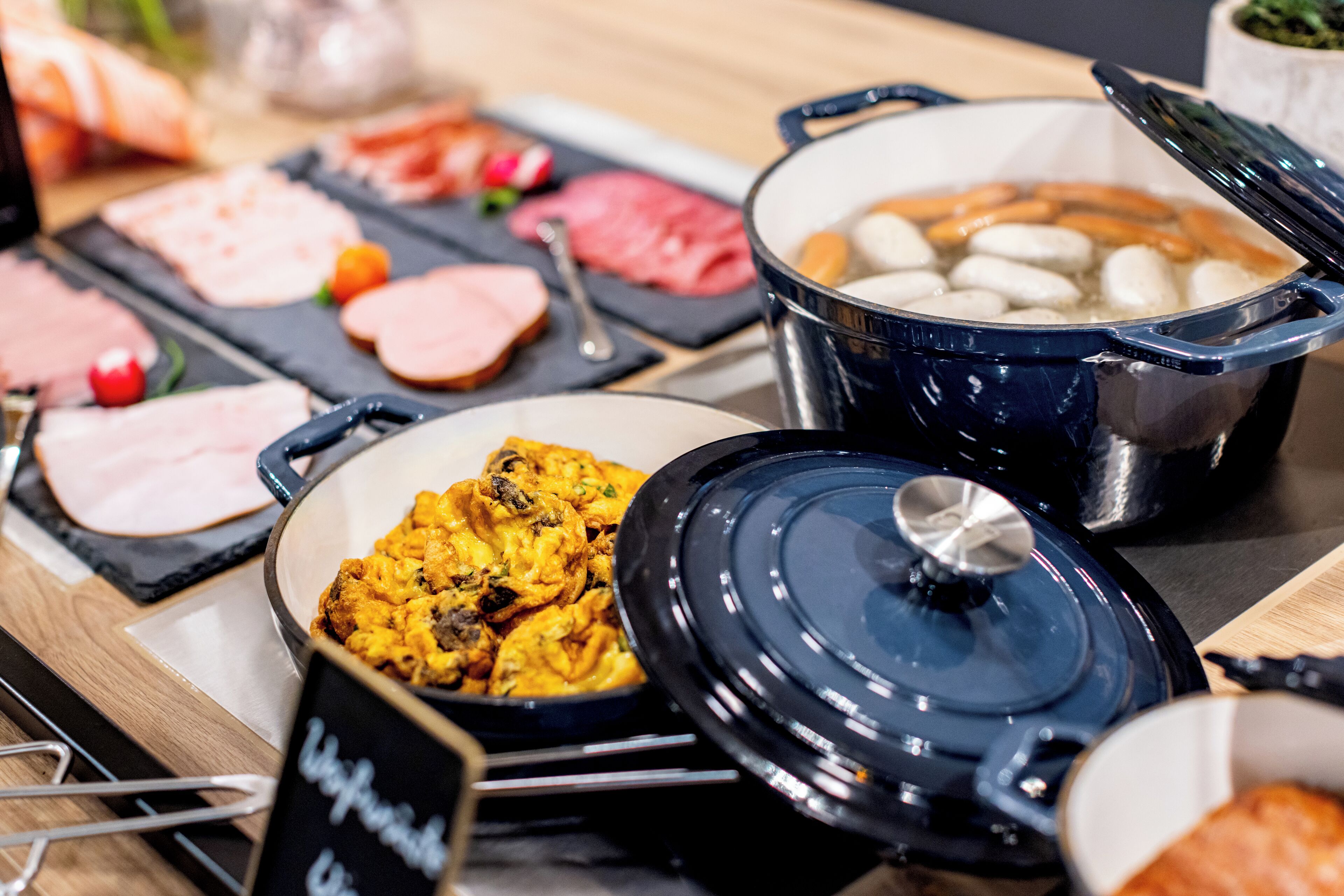 Ein Buffet mit verschiedenen Speisen, darunter Fleisch, Gemüse und einer Suppenterrine.