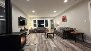 A living room with a fireplace, a sofa, a coffee table, and a television. - Nisswa Lake Hubert Cabin on Paul Bunyan Trail ~In the heart of Brainerd Lakes~ (Nisswa)
