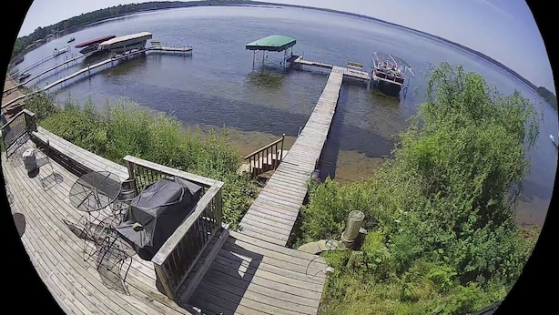 A wooden deck with a grill and outdoor seating, overlooking a calm lake with docks and boats. - Nisswa Lake Hubert Cabin on Paul Bunyan Trail ~In the heart of Brainerd Lakes~ (Nisswa)