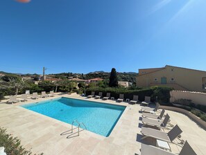 A swimming pool with lounge chairs and a view of a hillside.