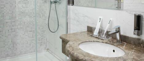 A modern bathroom with a glass-enclosed shower, a marble sink, and a large mirror.