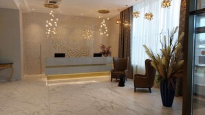 A modern reception area with a marble floor, a reception desk, two leather armchairs, and decorative lighting. - Best Western Plus Oskemen (Oskemen)