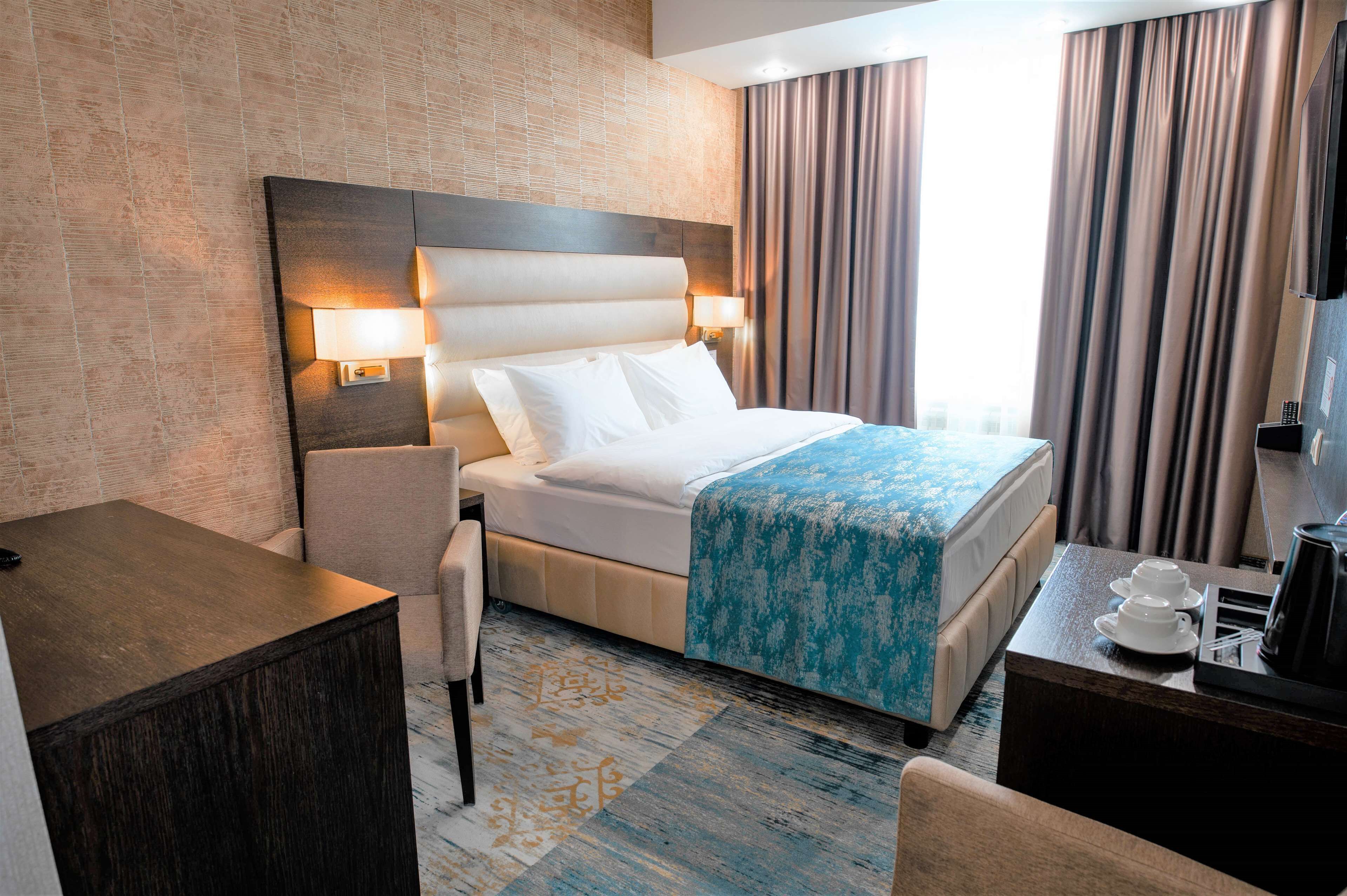 Una habitación de hotel con cama, mesita de noche y escritorio.